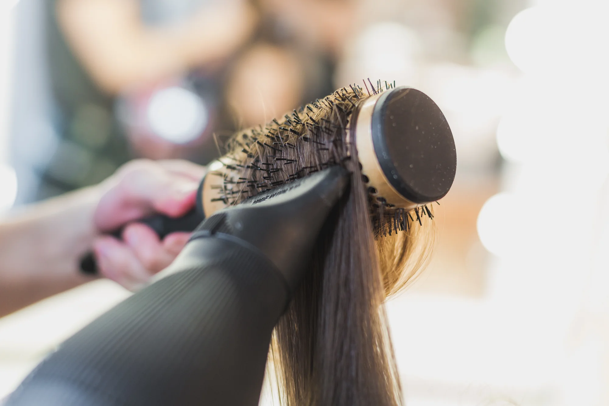 Stylist creating a smooth blowout with a round brush at Selfie Style Hair Design